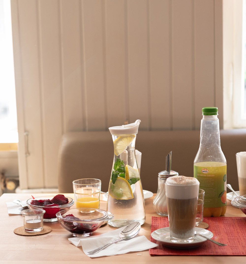 Tisch mit Frühstück - Kaffee, Teller, Blumenvase